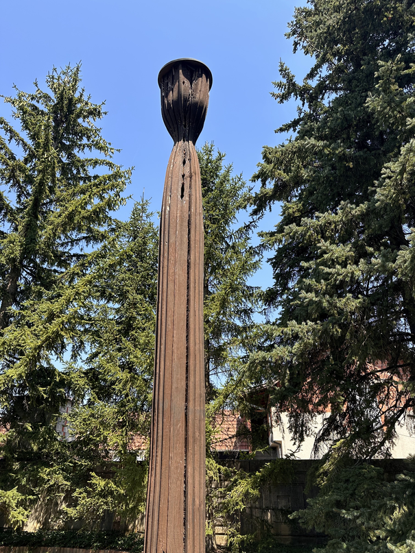 Tall wooden sculpture in the garden, like an oversized burnt matchstick